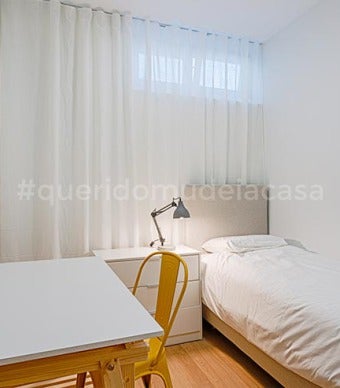 quarto de solteiro com uma secretária branca e uma cadeira amarela torrado , quadro de madeira e cortinado cinza claro
